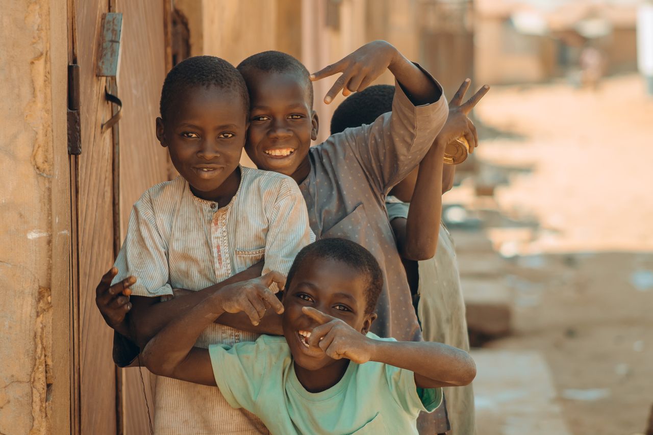gallery-6 Four cheerful children pose and play on a sunny day in an African neighborhood.